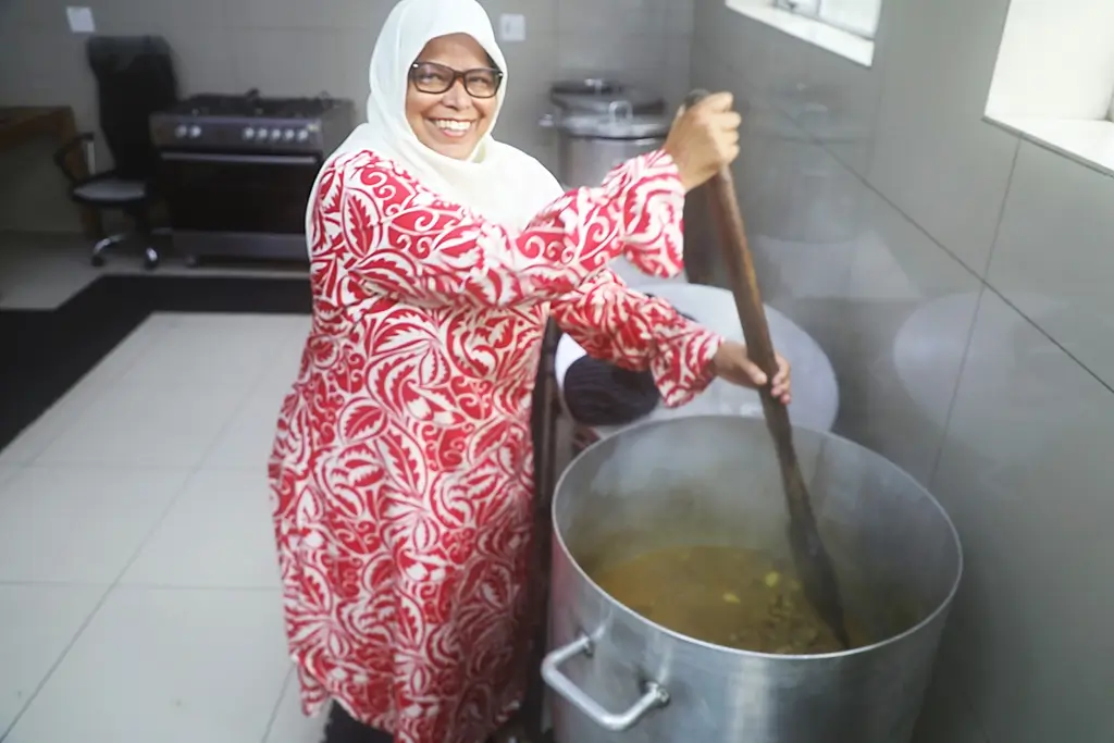 A woman prepares food in a very large cooking pot